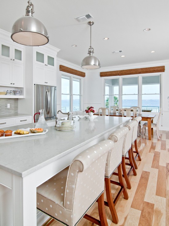 Światło i drewno Biała kuchnia łącząca drewno z nowoczesnym oświetleniem.