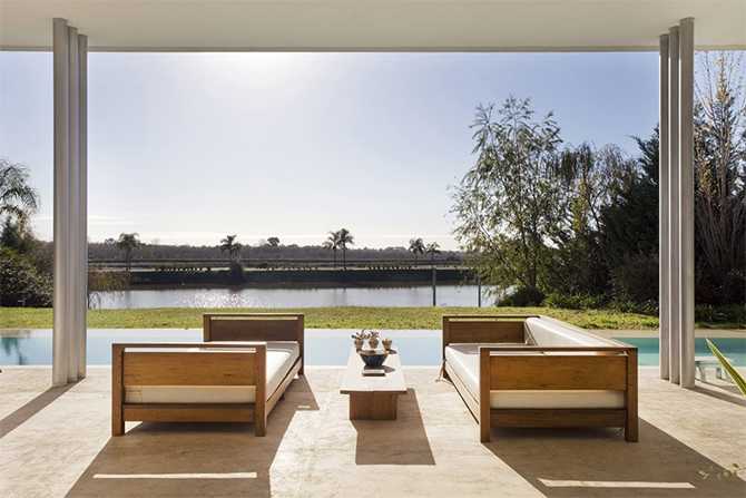 Beton i jezioro Strefa relaksu z widokiem na jezioro w domu z dużymi przeszkleniami i betonem.