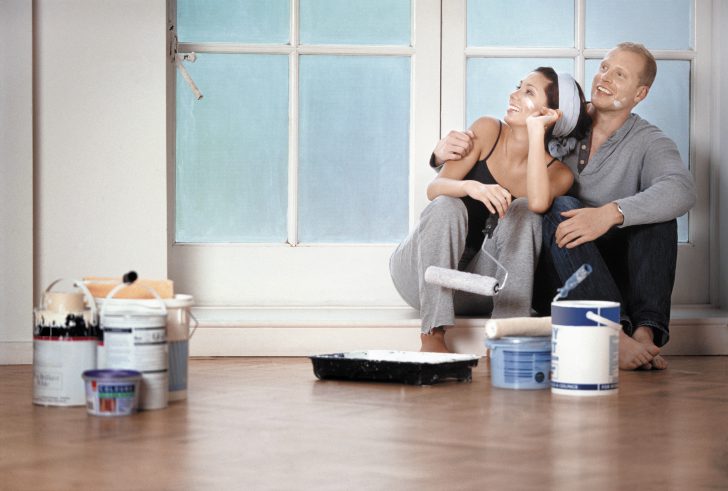 Malowanie ścian w kuchni Kobieta maluje ścianę w kuchni wałkiem – tani remont kuchni krok po kroku