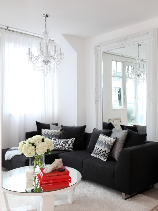 Świetlisty trik z lustrem Duże lustro w ramie odbija światło z okna, rozjaśniając mały salon.