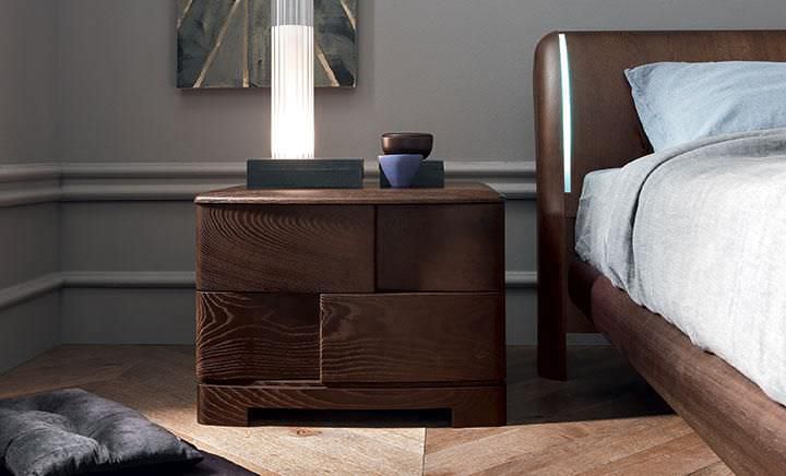 Komfort i styl w sypialni Stylowa szafka nocna z lampką, książką i zegarem w nowoczesnej sypialni.