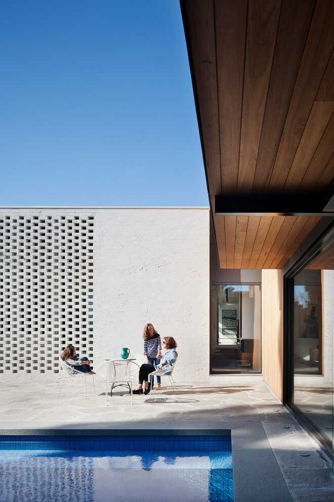 Strefa relaksu przy basenie Biała ściana z cegły z dekoracyjnym wzorem i strefa relaksu przy basenie