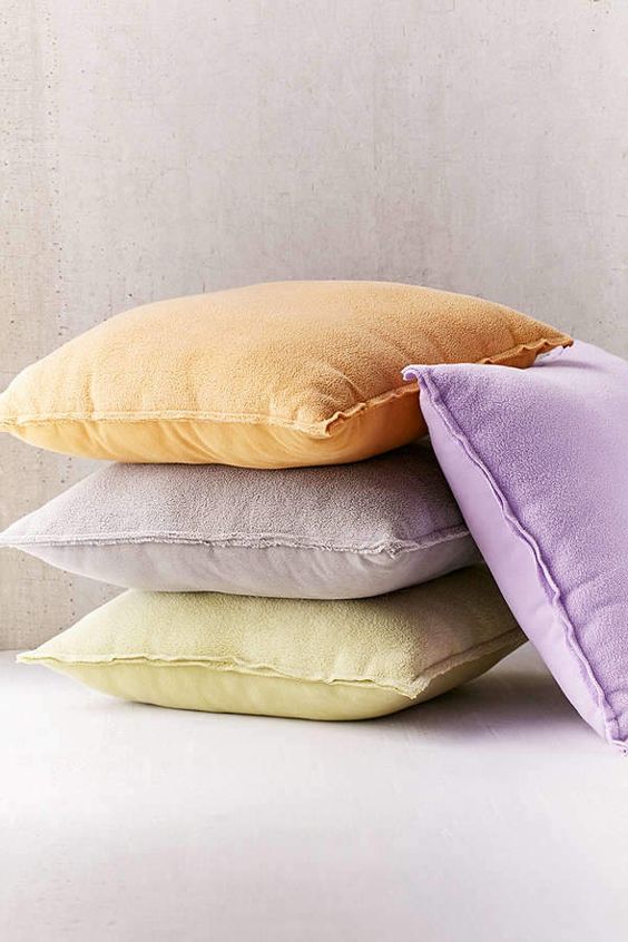 Zielony aksamit Aksamitne poduszki w różnych odcieniach zieleni na tle drewnianej ściany.