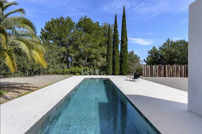 Ibizkański relaks przy basenie Basen przy willi na Ibizie: minimalistyczny design i relaks na świeżym powietrzu.